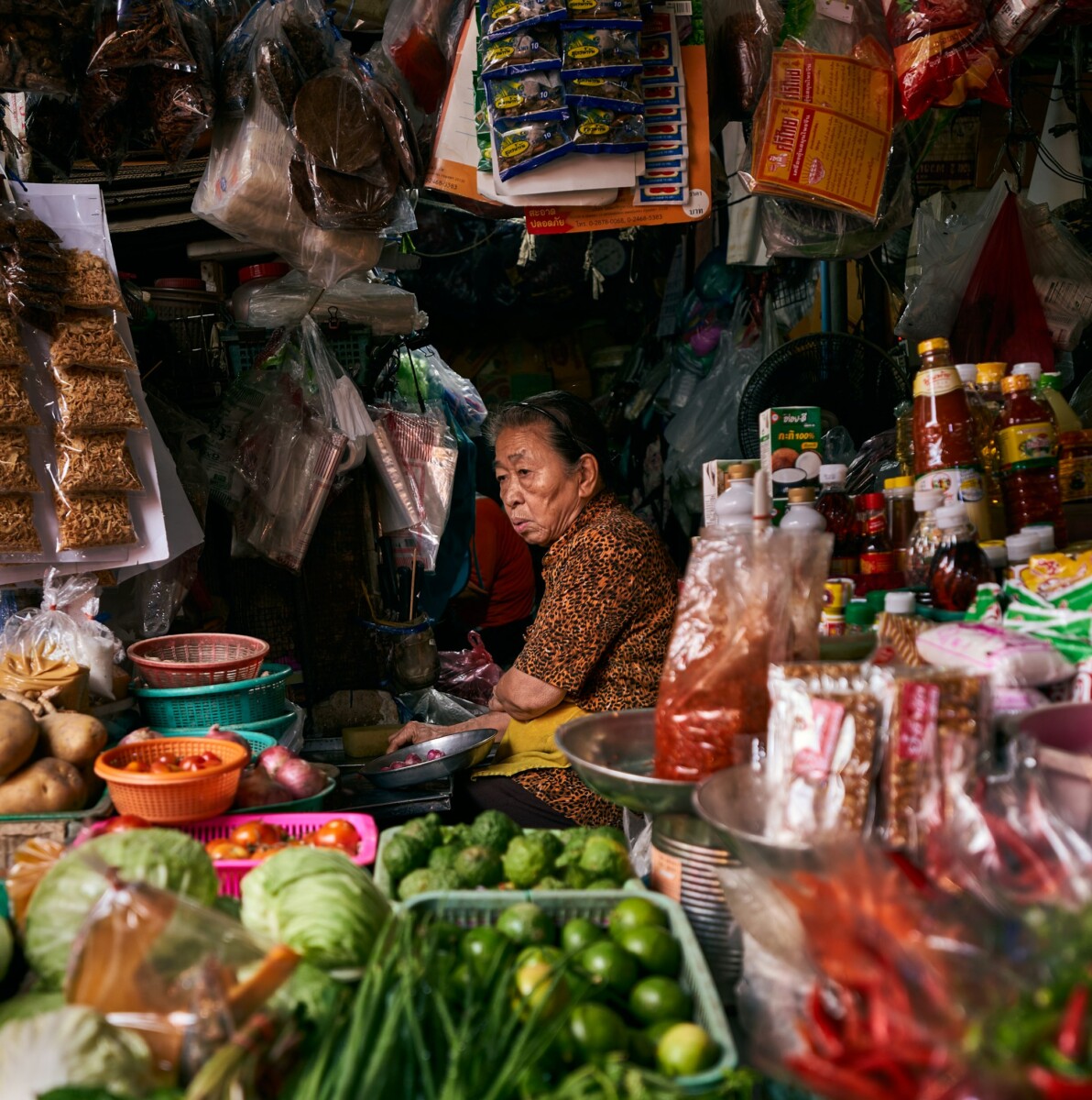 an old woman in a traditional market selling veggies